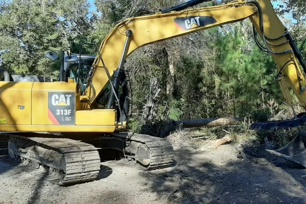 Yellow excavator in wooded area