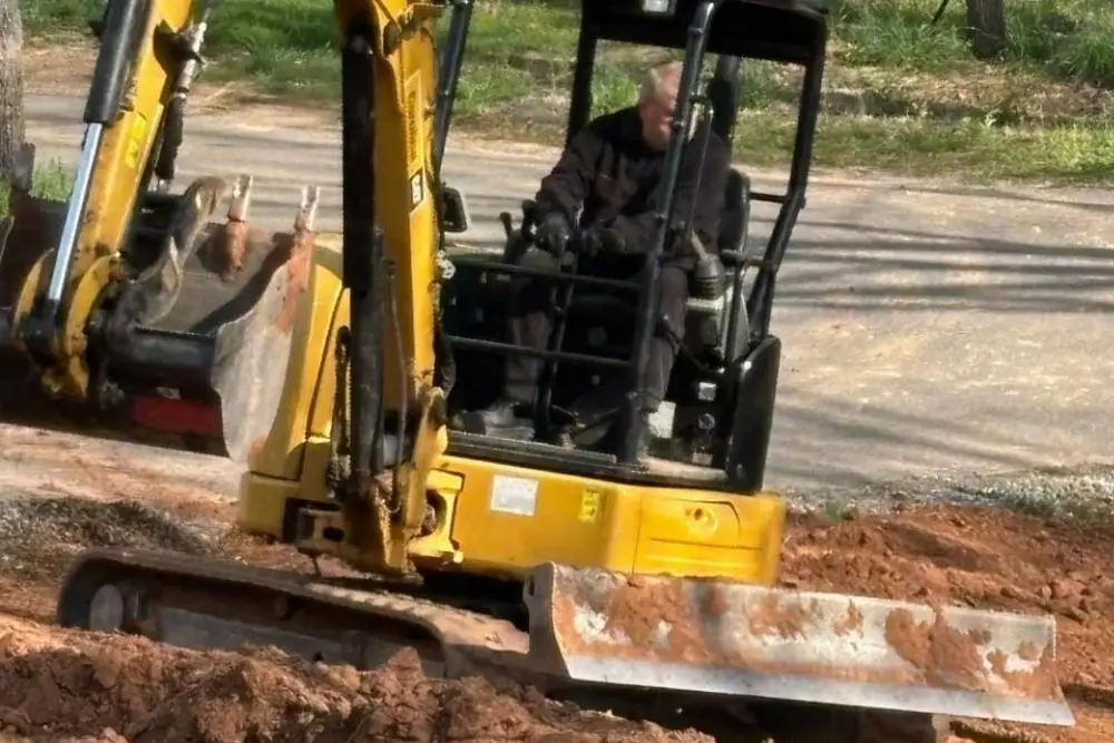 Man operating yellow excavator on site